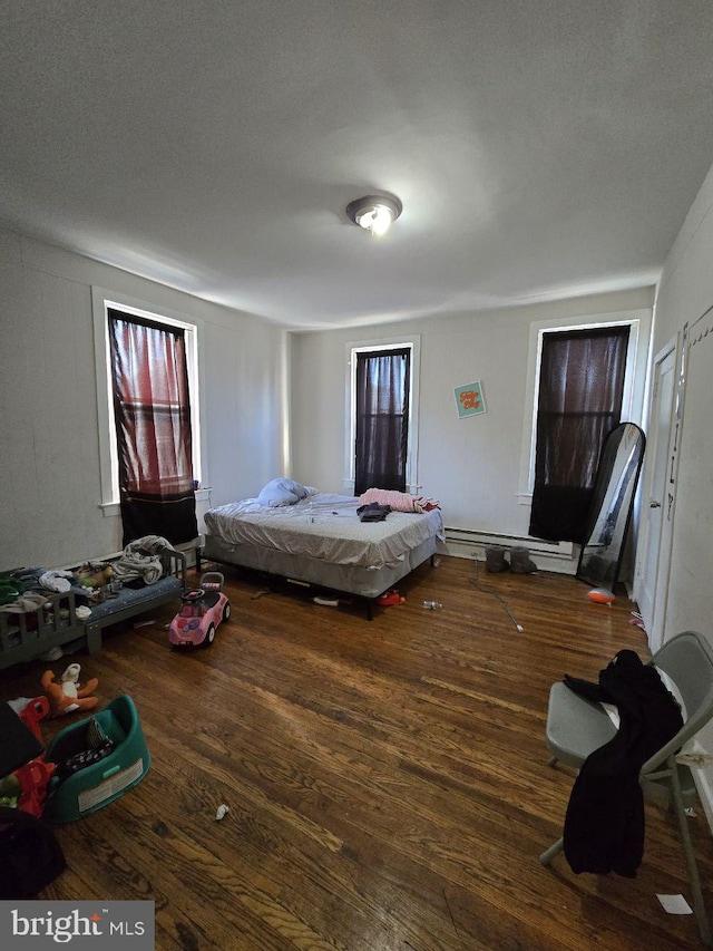 bedroom with a baseboard heating unit and wood finished floors