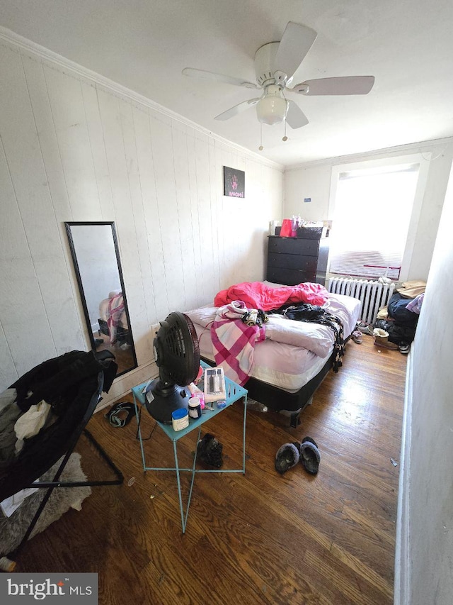 bedroom with radiator heating unit, crown molding, a ceiling fan, and wood finished floors