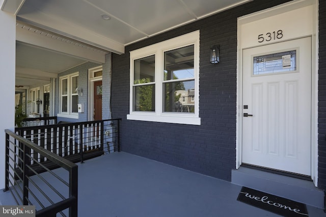 entrance to property featuring a porch and brick siding