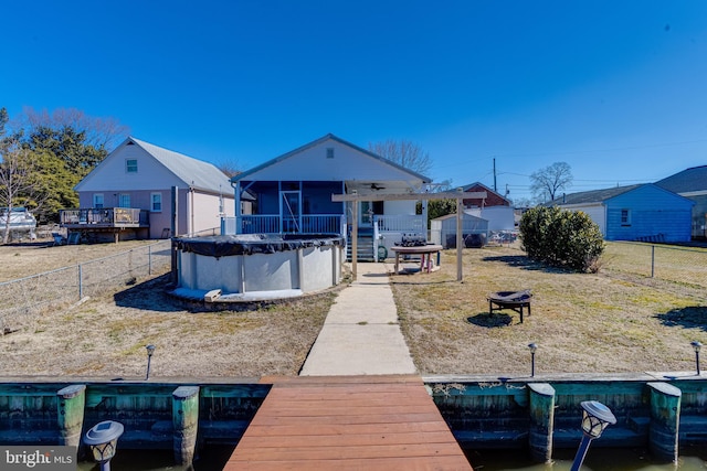 back of property with a fire pit, a fenced backyard, a sunroom, and a covered pool