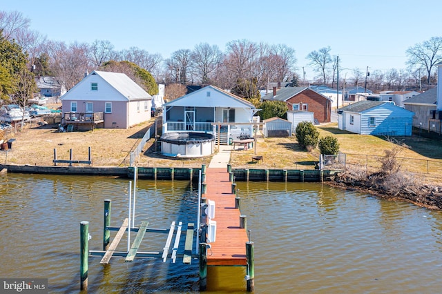 dock area featuring a fire pit, a residential view, a lawn, and boat lift