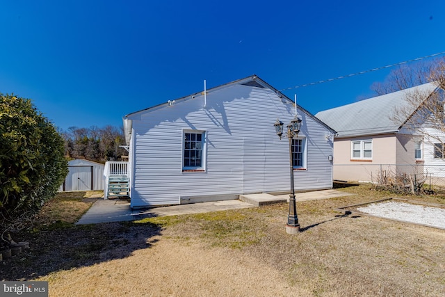 rear view of house featuring a storage shed, an outdoor structure, and fence