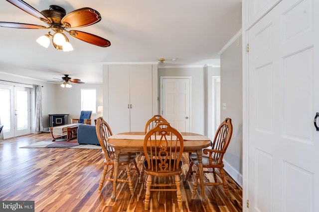 dining area with baseboards, ornamental molding, wood finished floors, and french doors