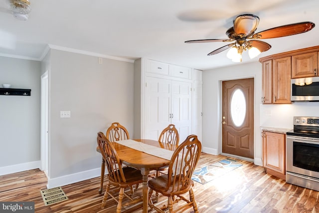 dining area featuring light wood-style flooring, ornamental molding, ceiling fan, and baseboards