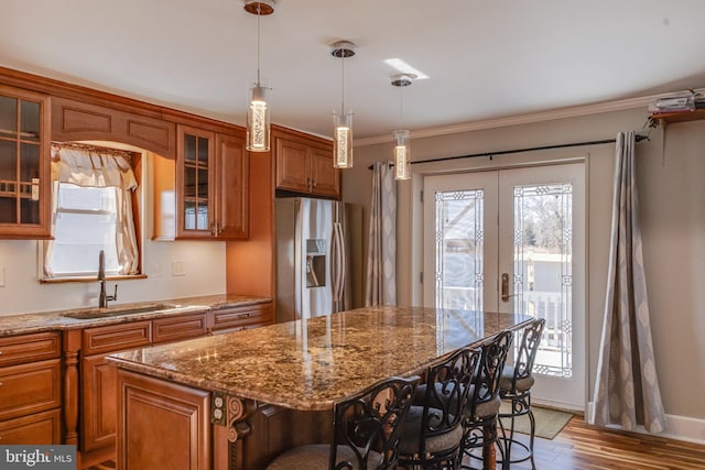 kitchen featuring a sink, french doors, brown cabinets, stainless steel fridge, and a kitchen bar