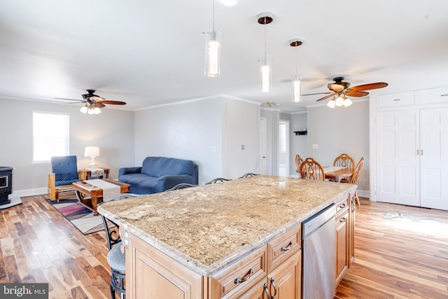 kitchen with light wood-style flooring, ornamental molding, open floor plan, a wood stove, and stainless steel dishwasher