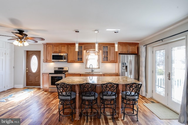 kitchen featuring a center island, brown cabinets, appliances with stainless steel finishes, a sink, and a kitchen breakfast bar