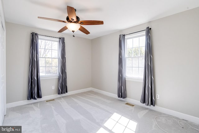 empty room with carpet floors, visible vents, ceiling fan, and baseboards