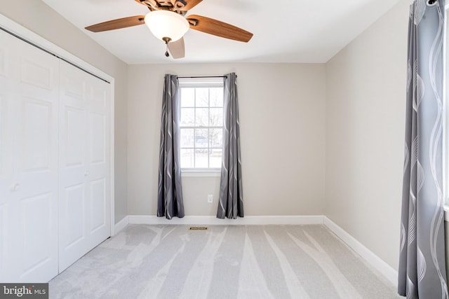 spare room featuring ceiling fan, visible vents, baseboards, and light colored carpet