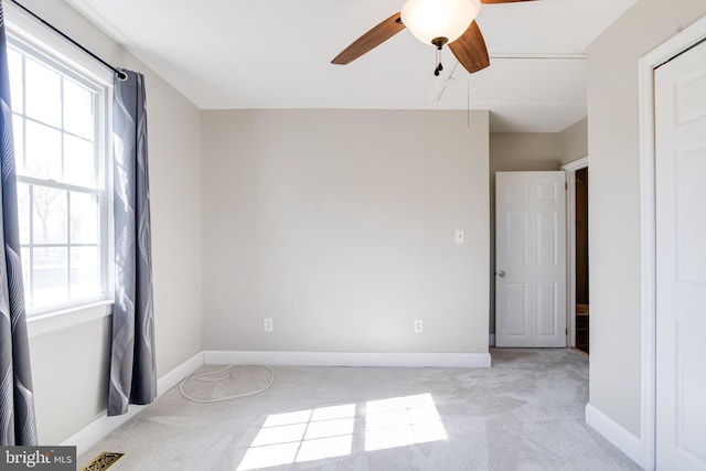 spare room featuring light colored carpet, visible vents, a ceiling fan, attic access, and baseboards