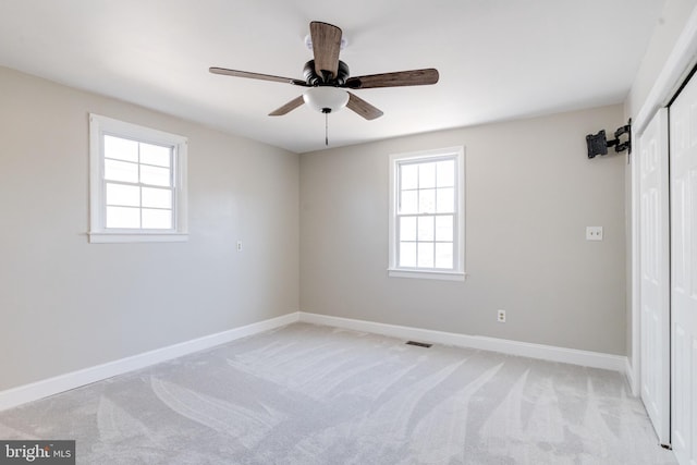 unfurnished room featuring light carpet, ceiling fan, visible vents, and baseboards