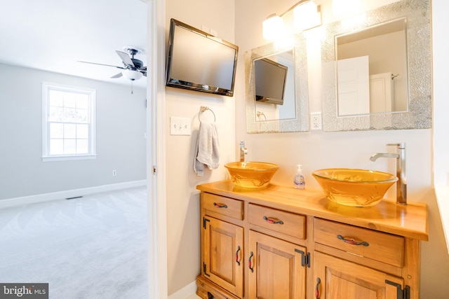 bathroom featuring double vanity, a ceiling fan, baseboards, and a sink