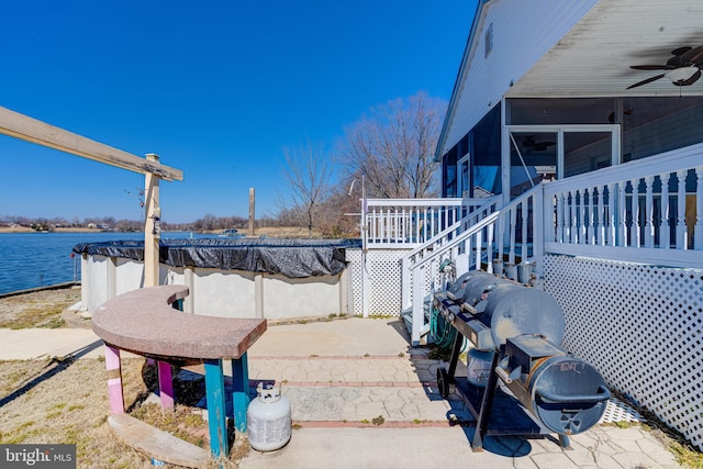 view of yard featuring a sunroom, a patio area, a water view, and ceiling fan