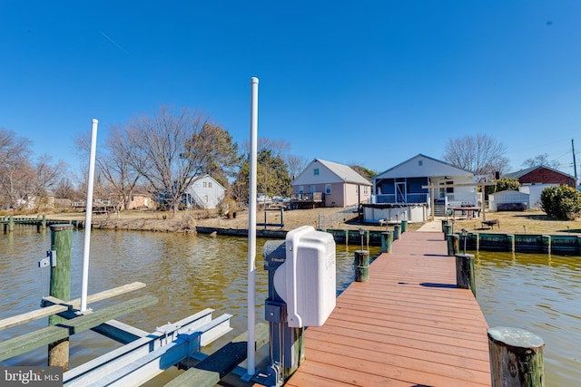 view of dock featuring a water view, boat lift, and a residential view