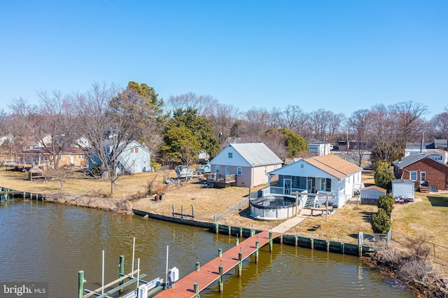 view of dock featuring a yard, an outdoor fire pit, a deck with water view, fence, and a residential view