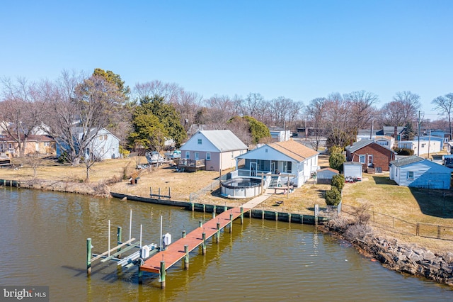 dock area with an outdoor fire pit, a deck with water view, a residential view, and a lawn