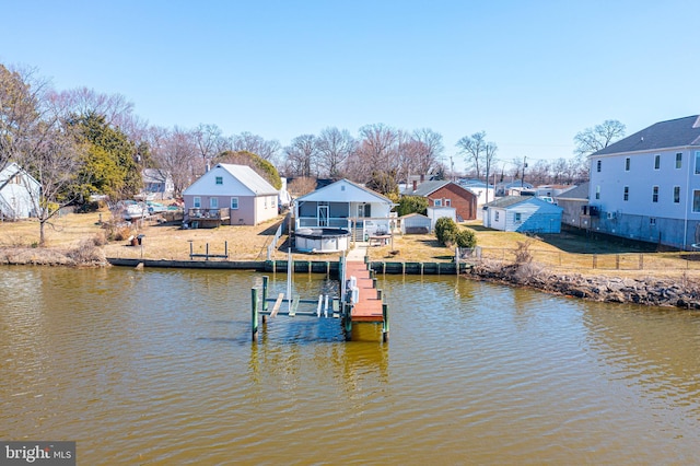 dock area with a residential view, a deck with water view, an outdoor fire pit, and a lawn