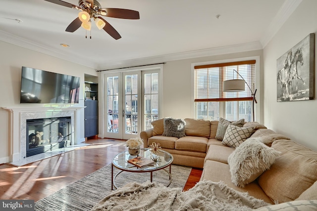 living area featuring a high end fireplace, french doors, crown molding, and wood finished floors