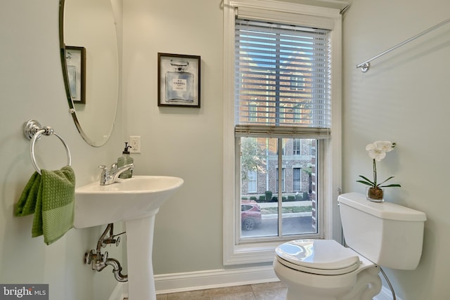 half bathroom with toilet, tile patterned flooring, and baseboards