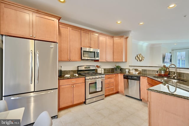 kitchen featuring recessed lighting, a sink, appliances with stainless steel finishes, dark stone counters, and crown molding