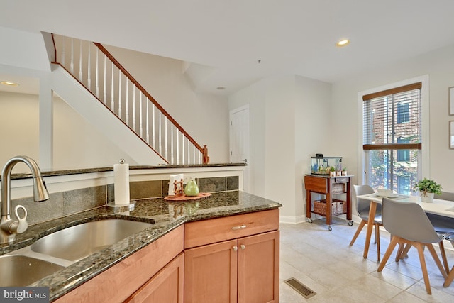 kitchen featuring recessed lighting, visible vents, a sink, dark stone counters, and baseboards