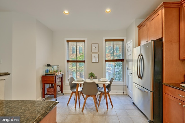 kitchen featuring light tile patterned flooring, recessed lighting, baseboards, freestanding refrigerator, and dark stone countertops