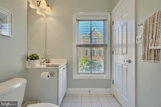 half bath featuring tile patterned flooring, baseboards, vanity, and toilet