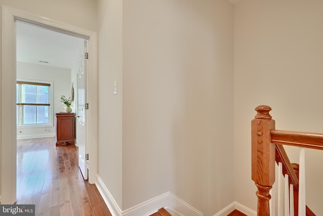 hallway with baseboards, hardwood / wood-style floors, and an upstairs landing