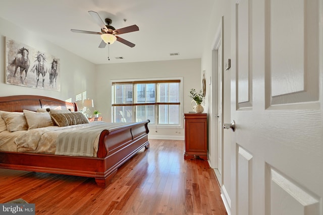 bedroom featuring a ceiling fan, wood-type flooring, visible vents, and baseboards