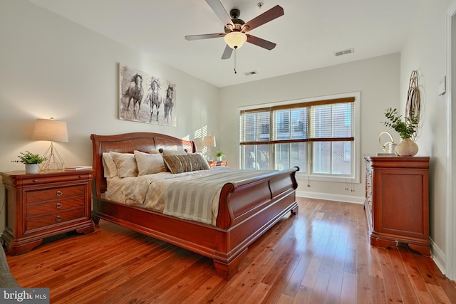 bedroom with baseboards, visible vents, ceiling fan, and hardwood / wood-style floors