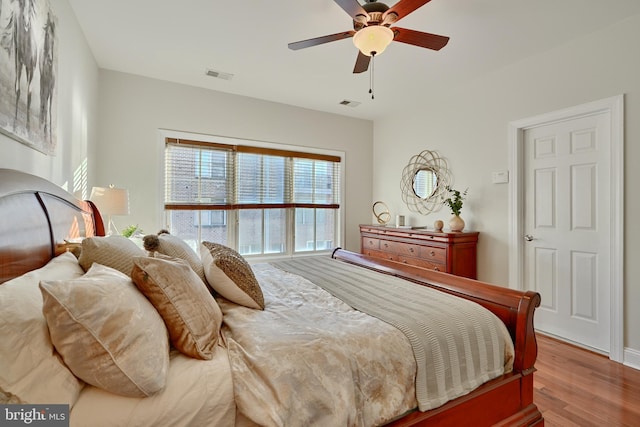 bedroom with a ceiling fan, visible vents, and wood finished floors