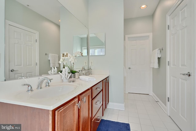 bathroom with double vanity, recessed lighting, a sink, tile patterned flooring, and baseboards