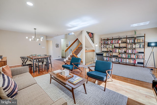 living area with a chandelier, stairway, baseboards, and wood finished floors