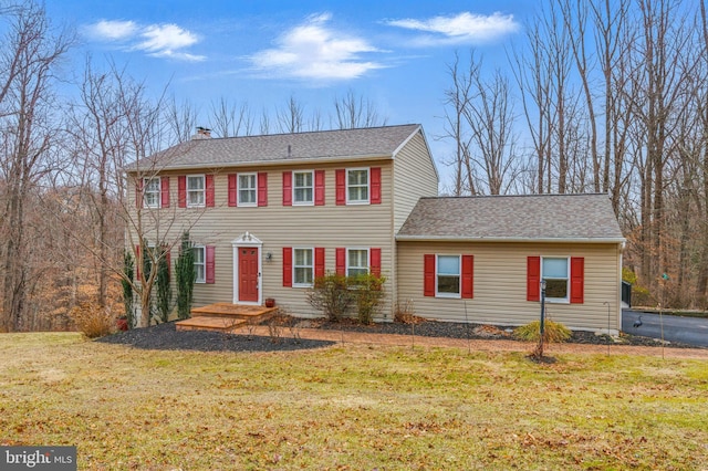 view of front of house featuring a chimney, a front lawn, and a shingled roof