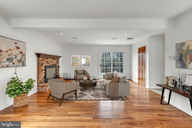 living room with visible vents, a brick fireplace, baseboards, recessed lighting, and light wood-style floors