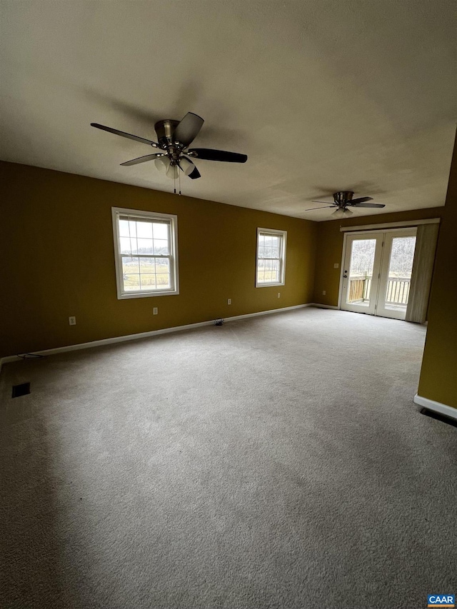 carpeted empty room with baseboards, visible vents, and a ceiling fan