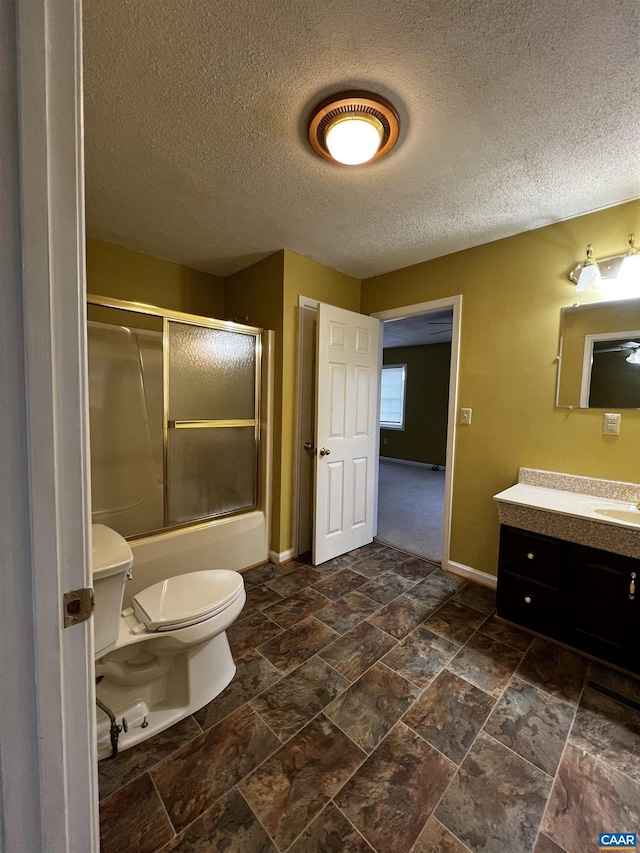 full bath featuring baseboards, bath / shower combo with glass door, toilet, stone finish flooring, and vanity