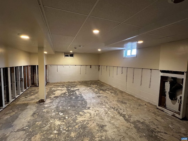 below grade area featuring a paneled ceiling and concrete block wall