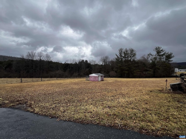 view of yard featuring a forest view, a storage unit, and an outbuilding