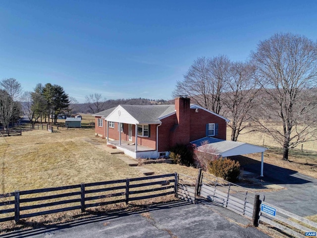 view of side of property featuring a fenced front yard, a chimney, aphalt driveway, and brick siding