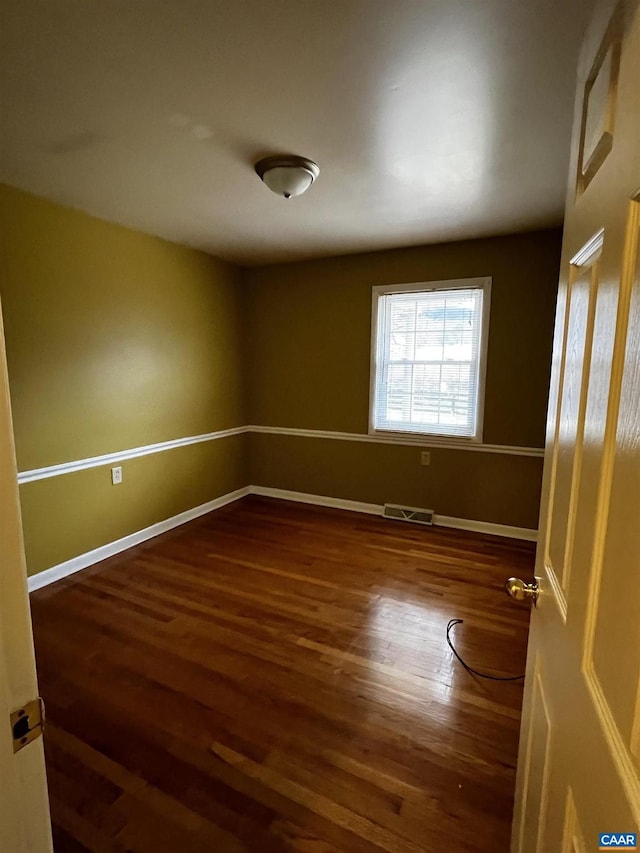 empty room with visible vents, baseboards, and wood finished floors