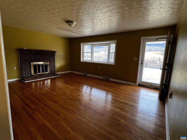 unfurnished living room featuring a wealth of natural light, visible vents, a textured ceiling, and wood finished floors