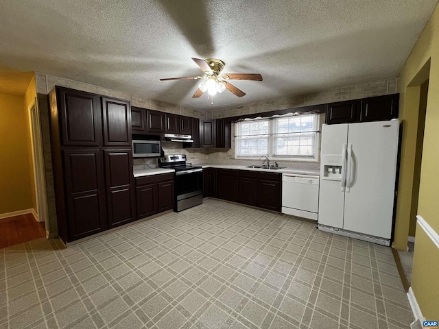 kitchen with light countertops, appliances with stainless steel finishes, a sink, and under cabinet range hood