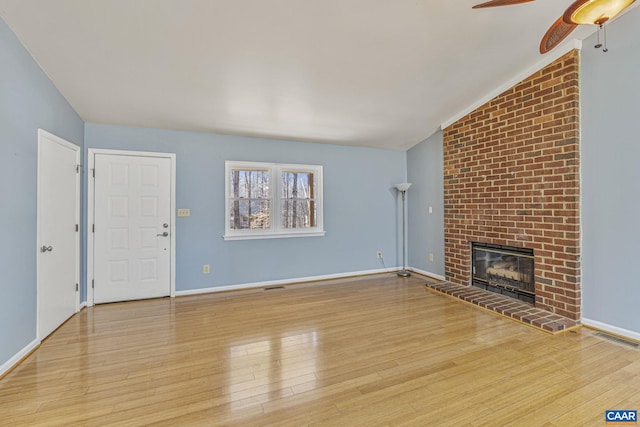 unfurnished living room featuring wood-type flooring, a fireplace, visible vents, and vaulted ceiling