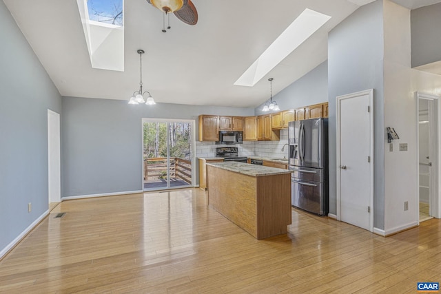 kitchen with a skylight, stainless steel fridge, electric range, a kitchen island, and black microwave