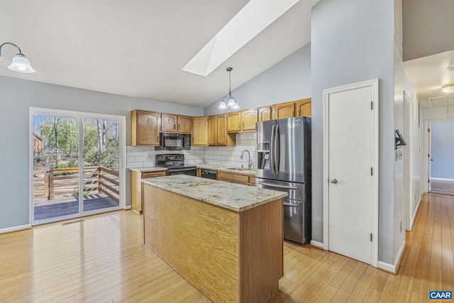 kitchen with a skylight, decorative backsplash, light wood-style flooring, black appliances, and a sink