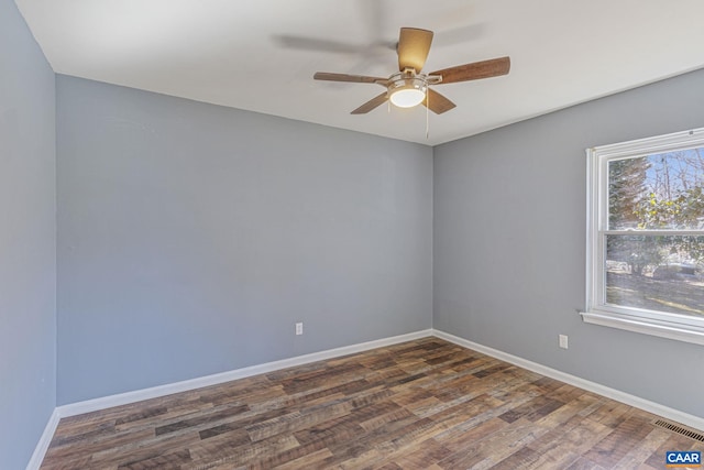 unfurnished room featuring a ceiling fan, wood finished floors, visible vents, and baseboards