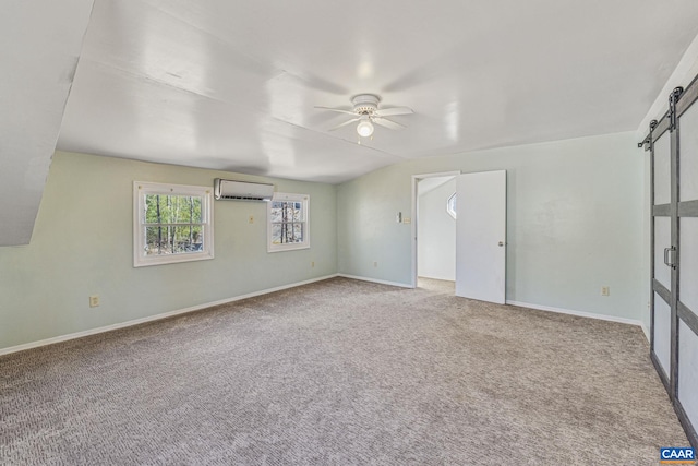 carpeted spare room with a barn door, baseboards, ceiling fan, and an AC wall unit