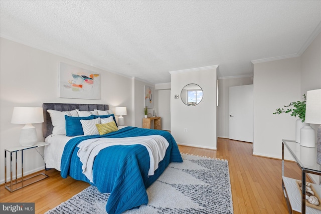 bedroom with crown molding, a textured ceiling, baseboards, and wood finished floors