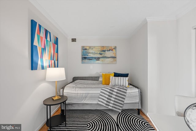 bedroom with baseboards, visible vents, wood finished floors, and ornamental molding